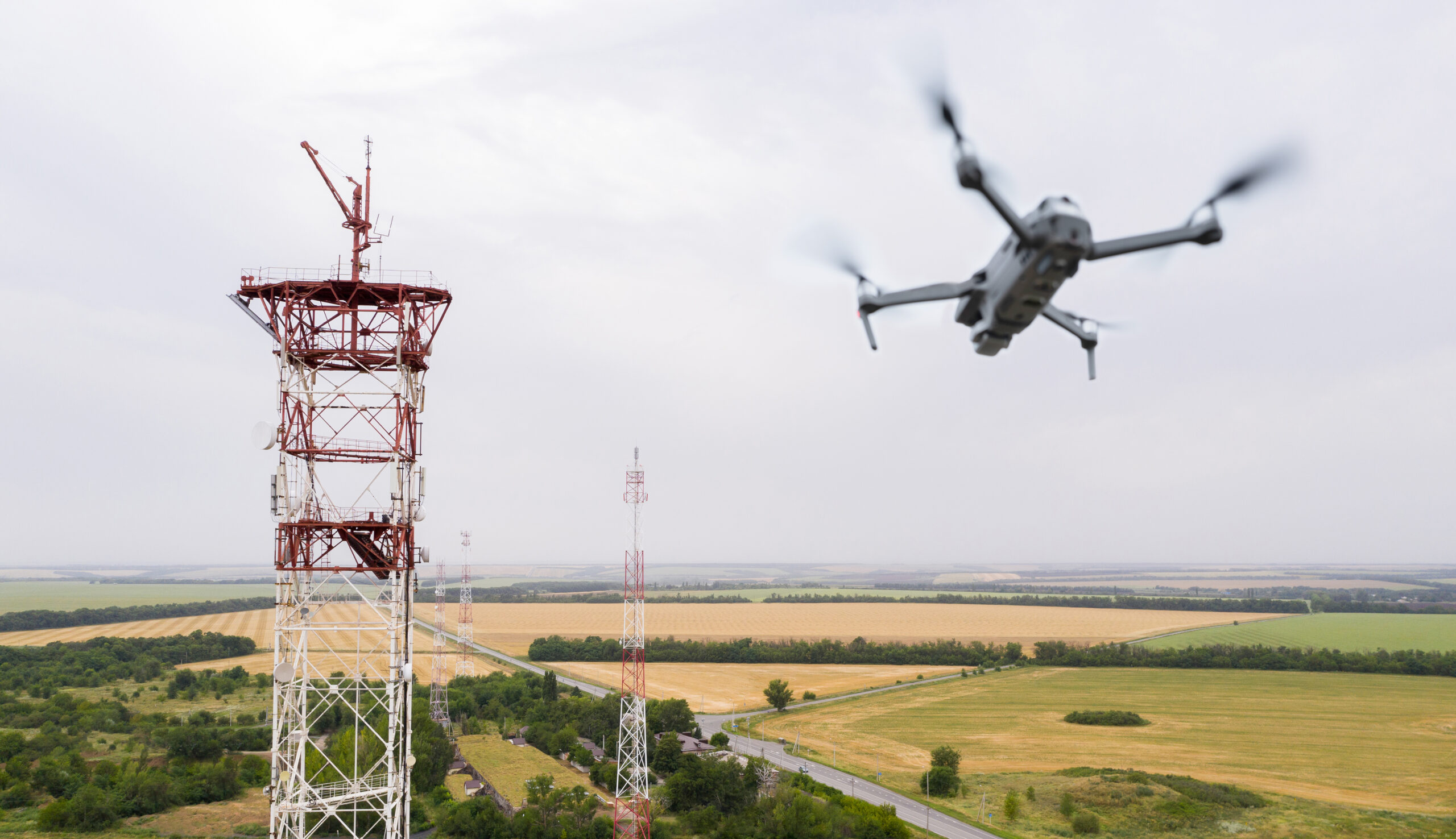 Photo of a drone in flight near a tower housing radio equipment 